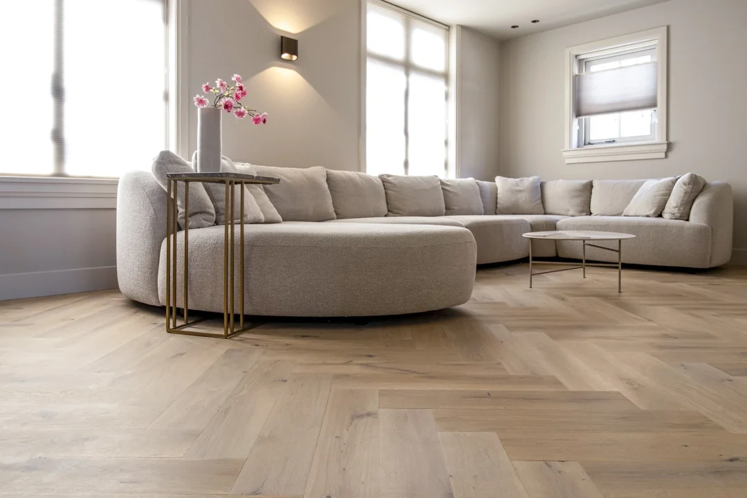 Woonkamer met grote bank en rustieke eiken visgraatvloer van Cinzento Custom Made®