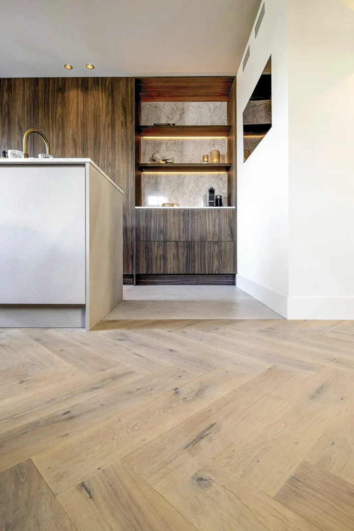 Moderne keuken met kookeiland en doorlopende houten visgraatvloer