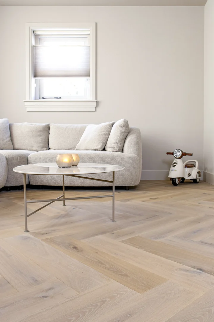 Visgraatvloer in moderne woonkamer met ruime zithoek en natuurlijke lichtinval