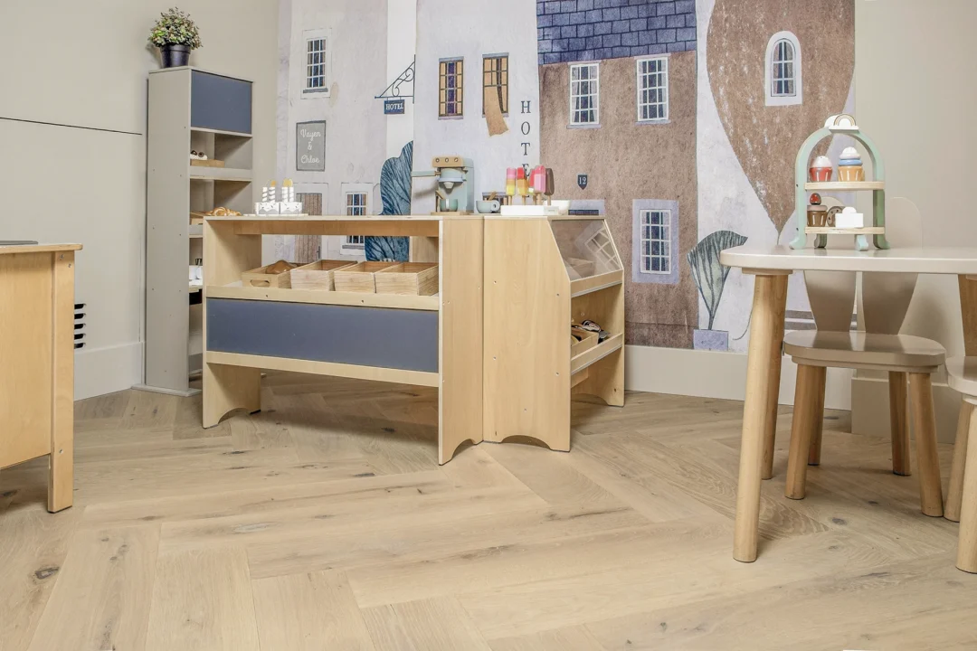 Speelruimte met kinderkeukentje en houten vloer in visgraatpatroon